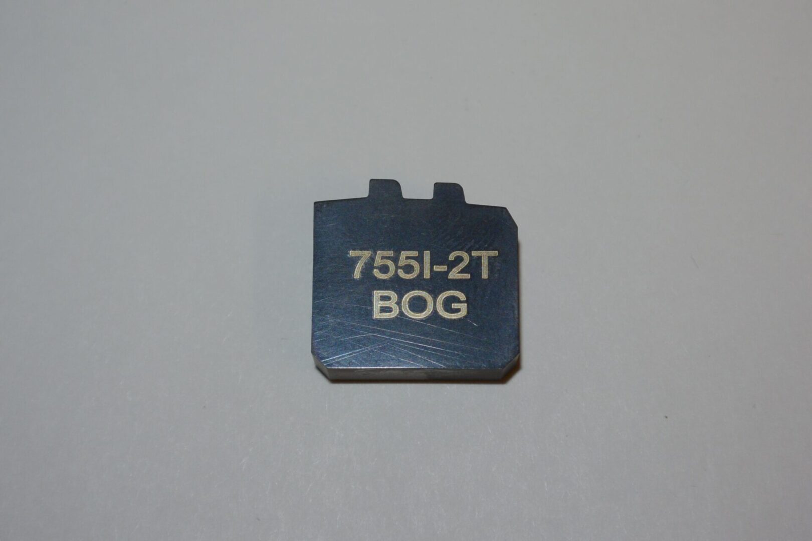 A small piece of metal with the words " 7 5 5 1-2 t " written on it.